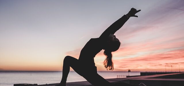 Kobieta ćwiczy jogę o poranku na plaży