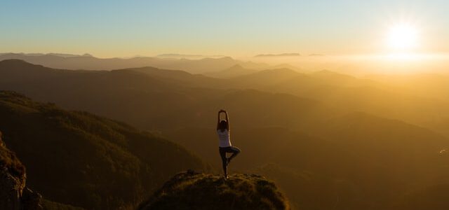 kobieta ćwiczy jogę o wschodzie słońca w górach